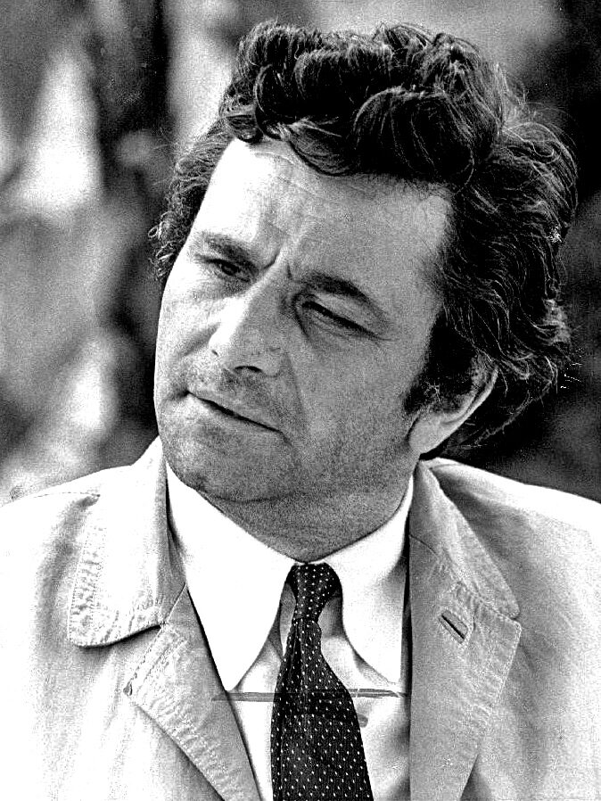 Actor Peter Falk as Lt Columbo, wearing a cream coloured jacket, white shirt and tie, while making his iconic inquisitive expression